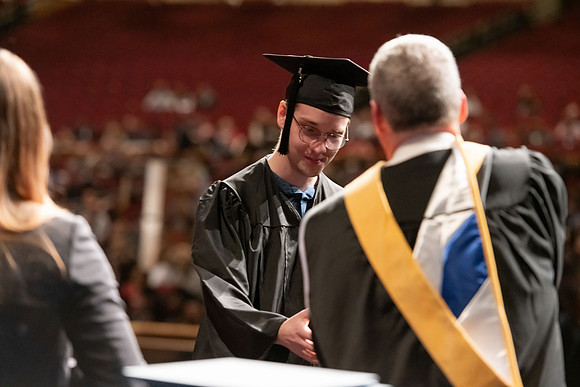 Graduates walk across the stage and accept their diploma.