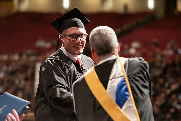 Graduates walk across the stage and accept their diploma.