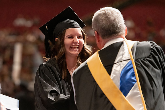 Graduates walk across the stage and accept their diploma.