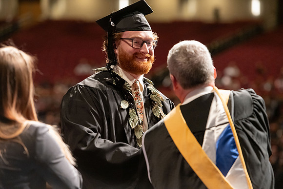 Graduates walk across the stage and accept their diploma.