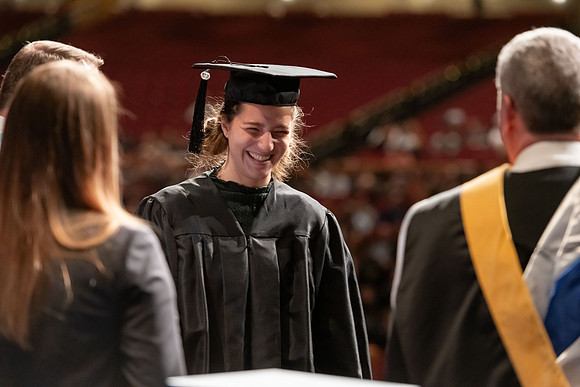 Graduates walk across the stage and accept their diploma.