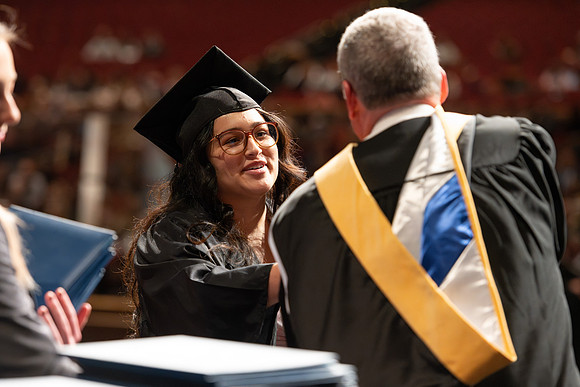 Graduates walk across the stage and accept their diploma.