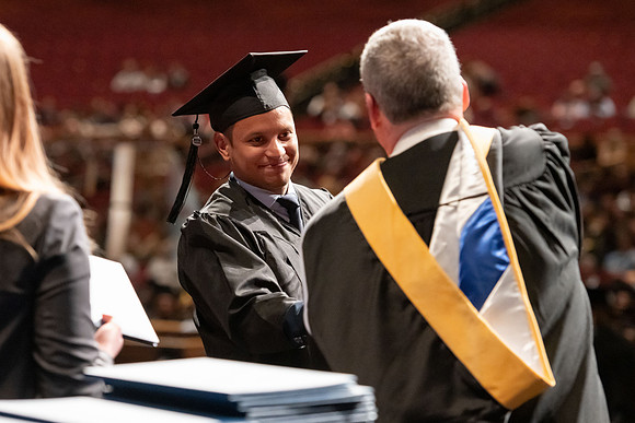 Graduates walk across the stage and accept their diploma.