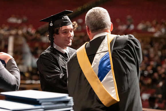 Graduates walk across the stage and accept their diploma.