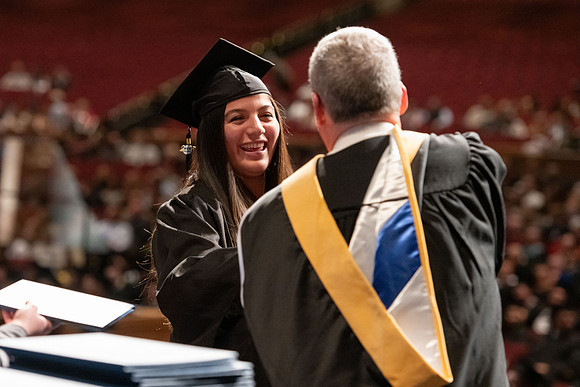 Graduates walk across the stage and accept their diploma.
