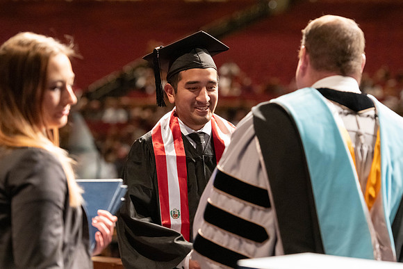 Graduates walk across the stage and accept their diploma.