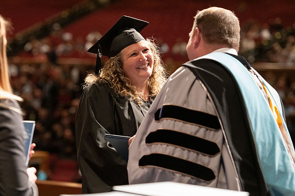 Graduates walk across the stage and accept their diploma.
