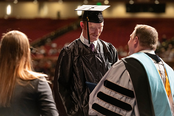 Graduates walk across the stage and accept their diploma.
