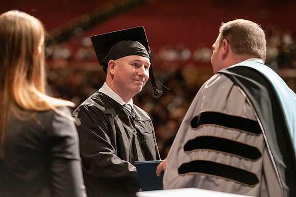 Graduates walk across the stage and accept their diploma.