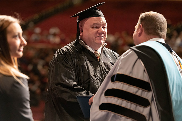 Graduates walk across the stage and accept their diploma.
