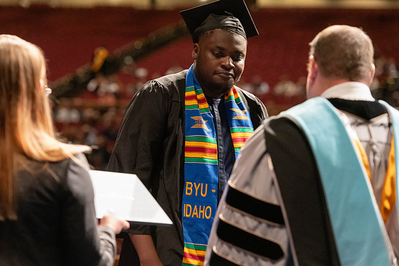 Graduates walk across the stage and accept their diploma.