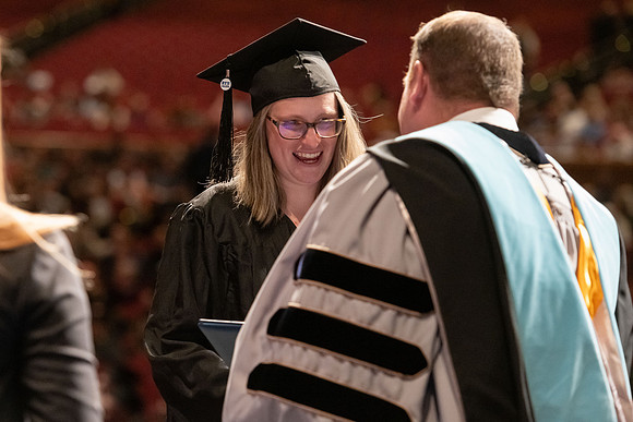 Graduates walk across the stage and accept their diploma.