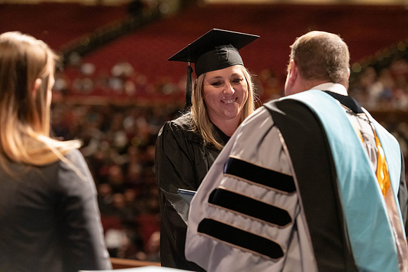 Graduates walk across the stage and accept their diploma.