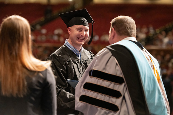 Graduates walk across the stage and accept their diploma.