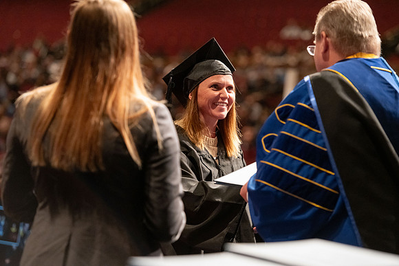 Graduates walk across the stage and accept their diploma.