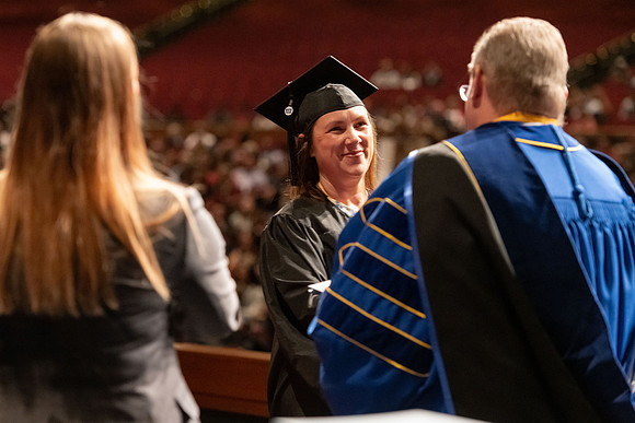 Graduates walk across the stage and accept their diploma.