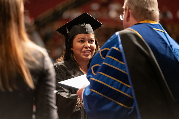 Graduates walk across the stage and accept their diploma.