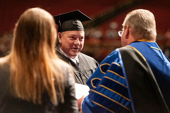 Graduates walk across the stage and accept their diploma.