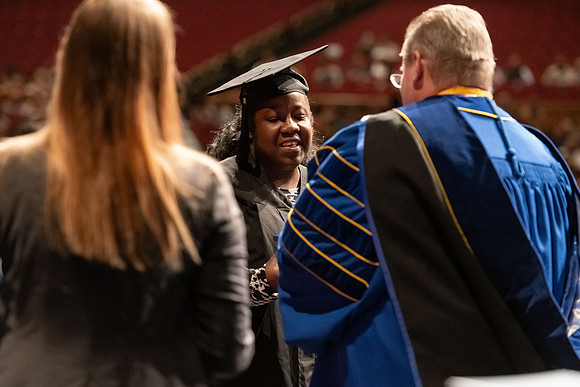 Graduates walk across the stage and accept their diploma.