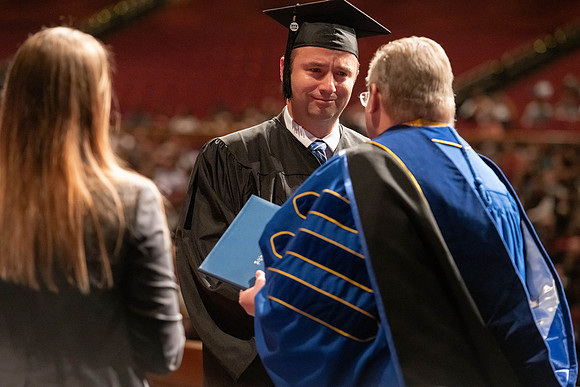 Graduates walk across the stage and accept their diploma.