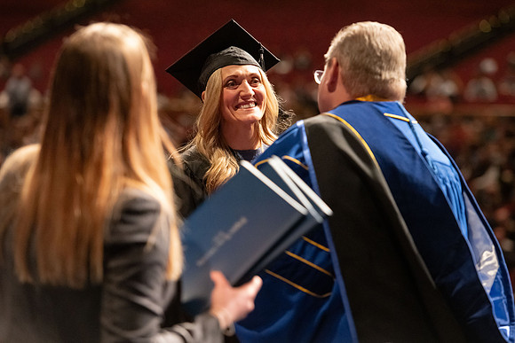 Graduates walk across the stage and accept their diploma.