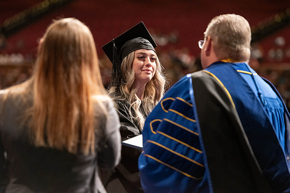 Graduates walk across the stage and accept their diploma.