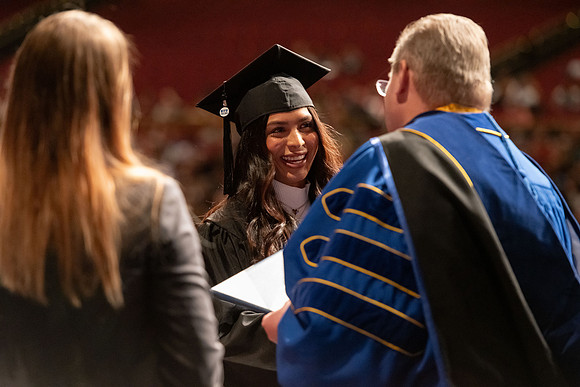 Graduates walk across the stage and accept their diploma.