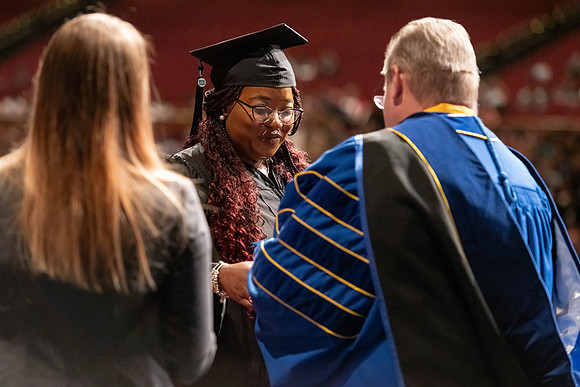 Graduates walk across the stage and accept their diploma.