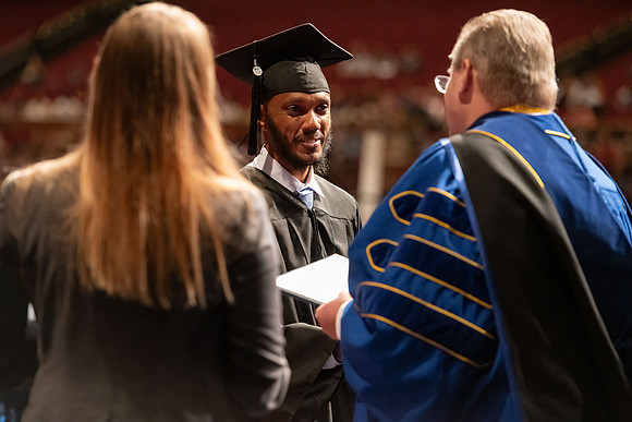 Graduates walk across the stage and accept their diploma.