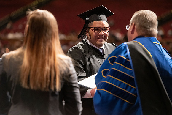 Graduates walk across the stage and accept their diploma.