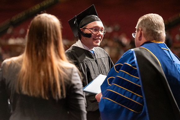 Graduates walk across the stage and accept their diploma.