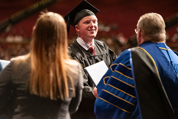 Graduates walk across the stage and accept their diploma.