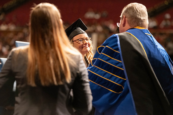 Graduates walk across the stage and accept their diploma.