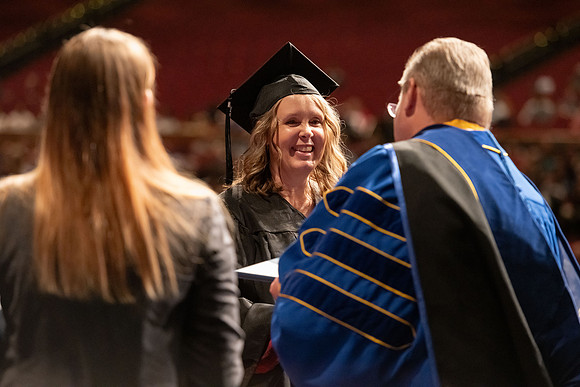 Graduates walk across the stage and accept their diploma.