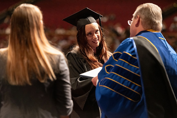 Graduates walk across the stage and accept their diploma.