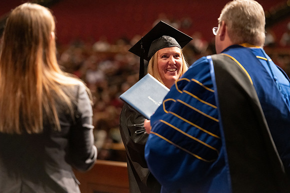 Graduates walk across the stage and accept their diploma.