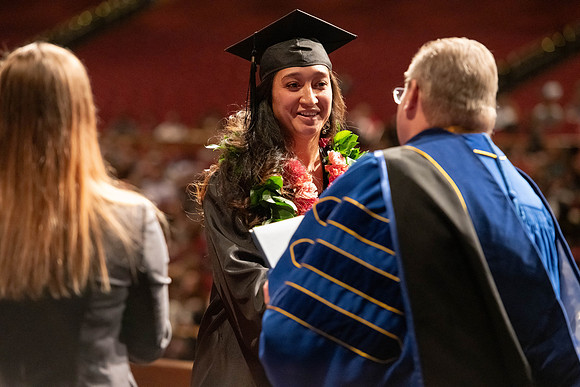 Graduates walk across the stage and accept their diploma.