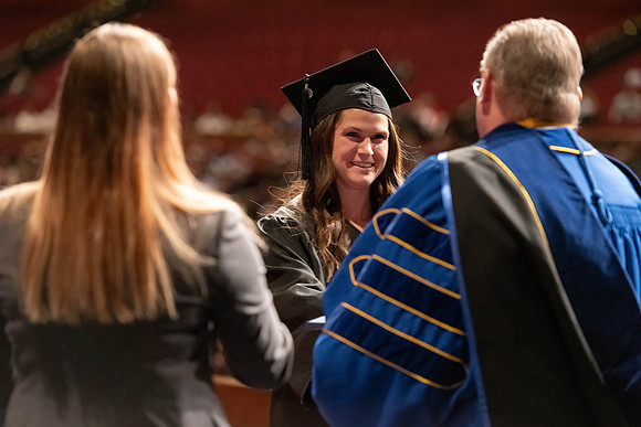 Graduates walk across the stage and accept their diploma.