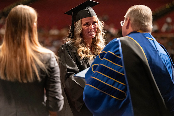 Graduates walk across the stage and accept their diploma.