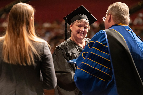 Graduates walk across the stage and accept their diploma.