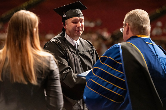 Graduates walk across the stage and accept their diploma.