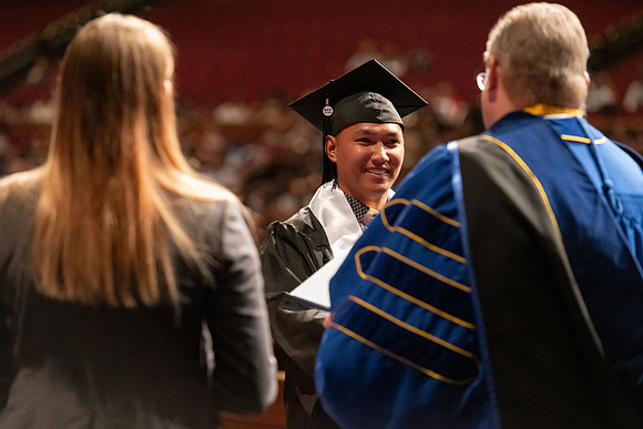 Graduates walk across the stage and accept their diploma.