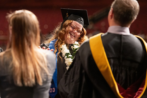 Graduates walk across the stage and accept their diploma.