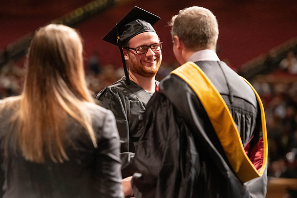 Graduates walk across the stage and accept their diploma.