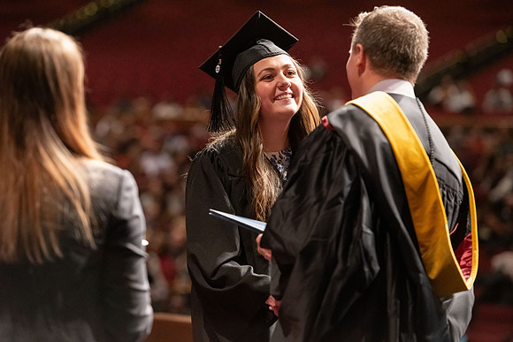 Graduates walk across the stage and accept their diploma.