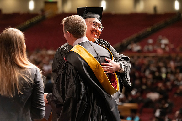 Graduates walk across the stage and accept their diploma.