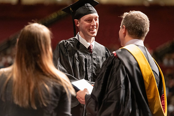 Graduates walk across the stage and accept their diploma.