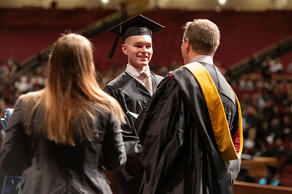 Graduates walk across the stage and accept their diploma.