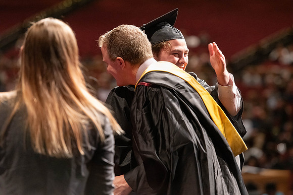 Graduates walk across the stage and accept their diploma.
