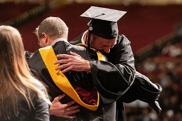 Graduates walk across the stage and accept their diploma.